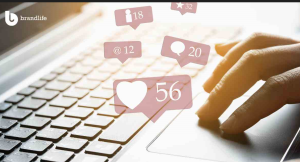 A person’s hands are actively typing on a laptop keyboard, bathed in warm natural light. Floating above are social media marketing engagement icons, including likes, comments, favorites, mentions, and upvotes, symbolizing the dynamic and interactive nature of online marketing metrics.